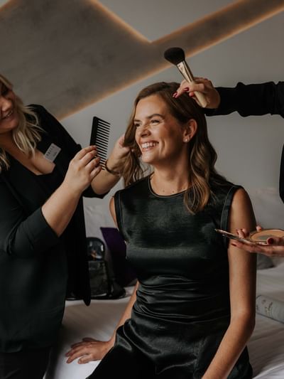 Two individuals giving a beauty makeover to a seated person at Sofitel Brisbane Central