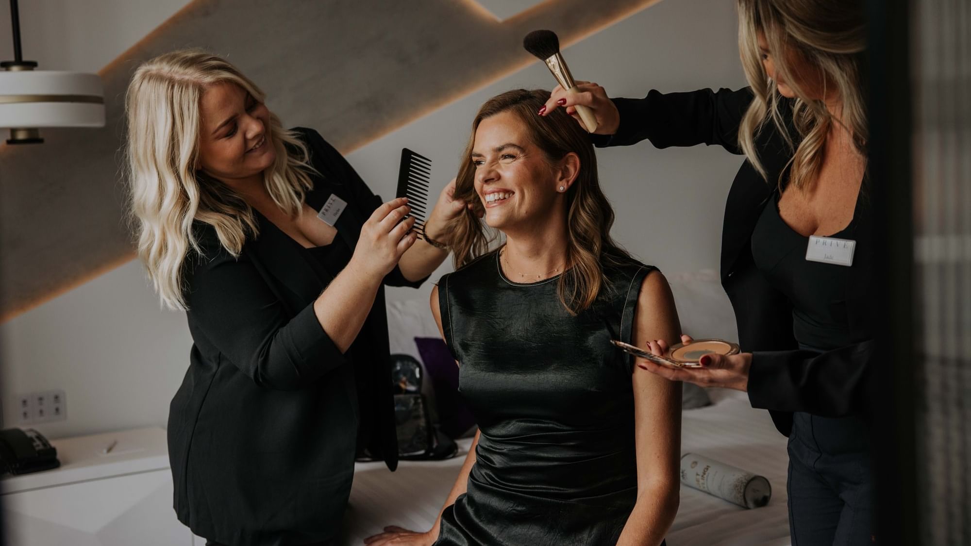 Three stylists attending to a client's hair and makeup in a room at Sofitel Brisbane Central