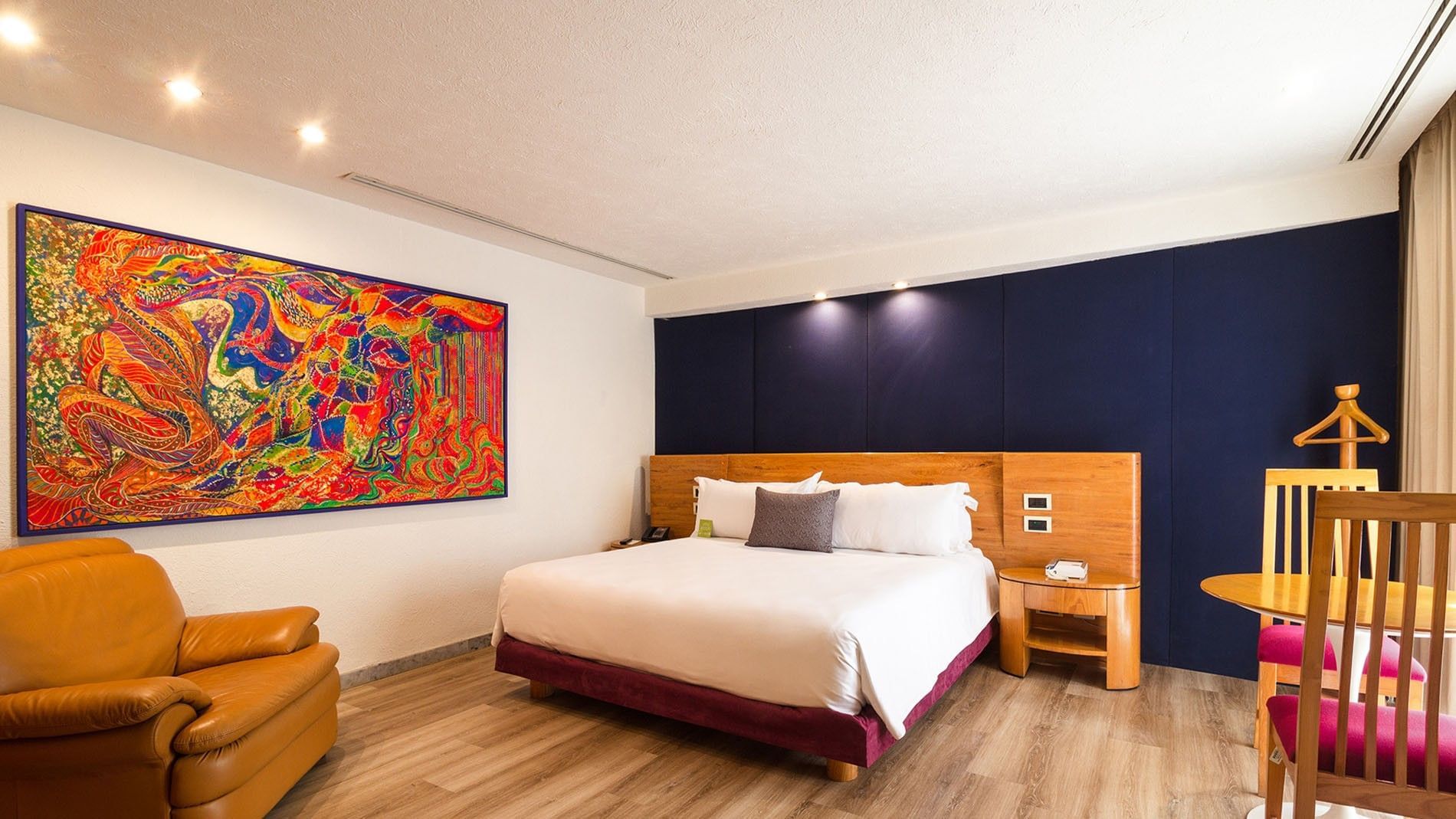 King Camichin Suite at Camino Real Guadalajara with a plush leather chair and colorful abstract wall painting