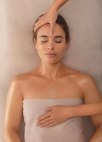 A woman enjoys a forehead massage under a light sheet at The Saujana Hotel Kuala Lumpur