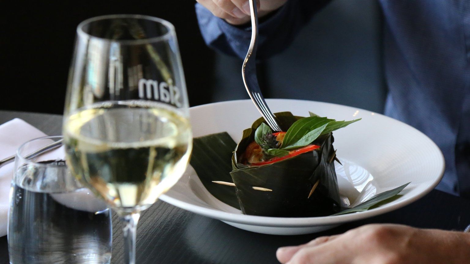 Guest enjoying Thai Barcelona dish with champagne at Warwick Le Crystal