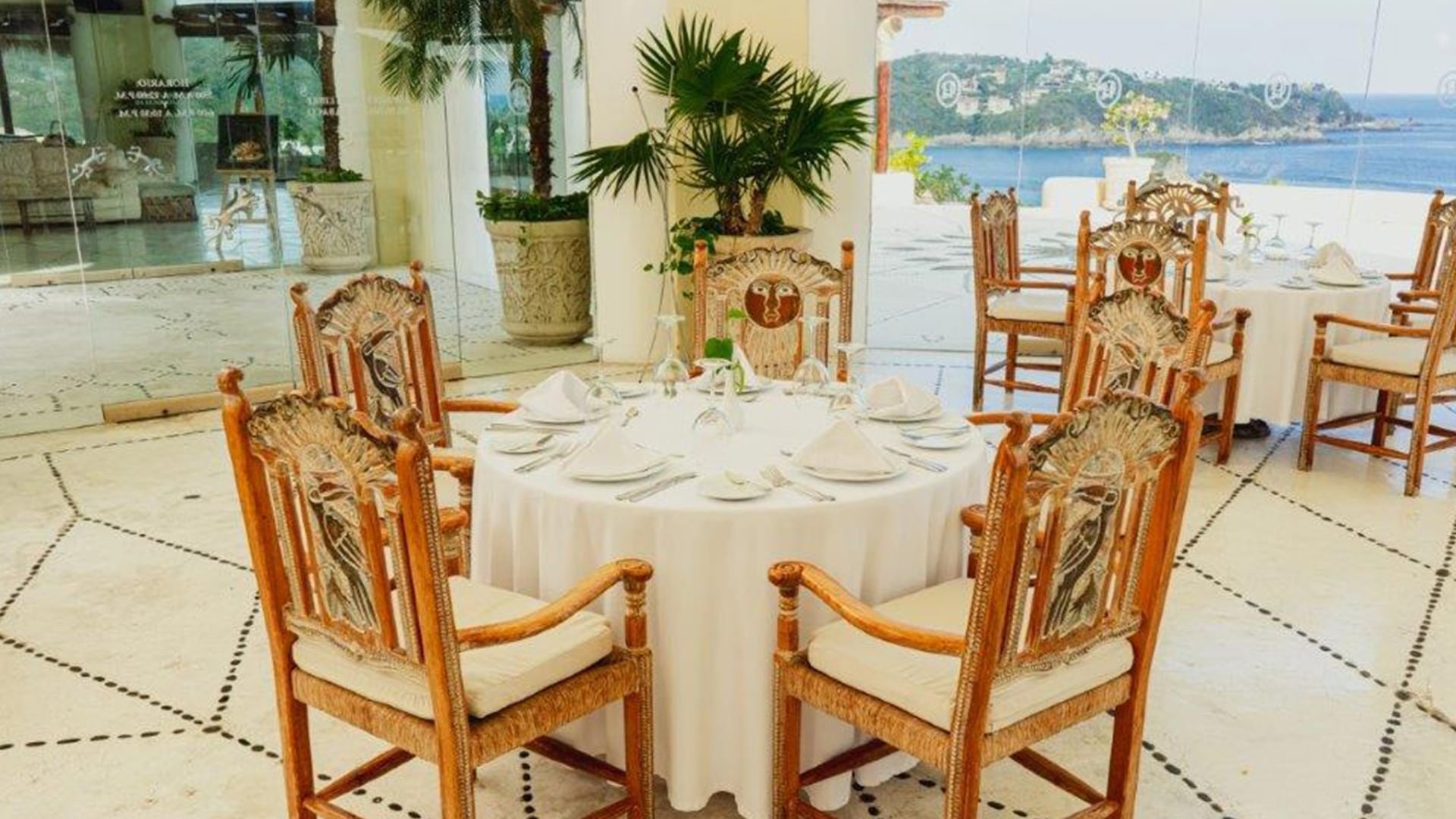 Tierra Mia restaurant featuring sun-carved chairs around a round table with plates at Quinta Real Huatulco
