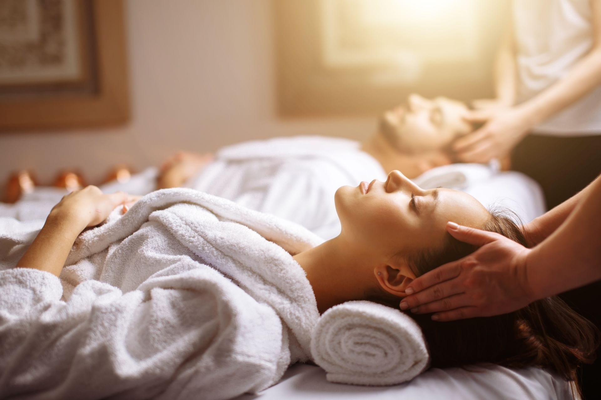 Couple in white robes enjoying relaxing head massages during a spa treatment session at El Conquistador Resort