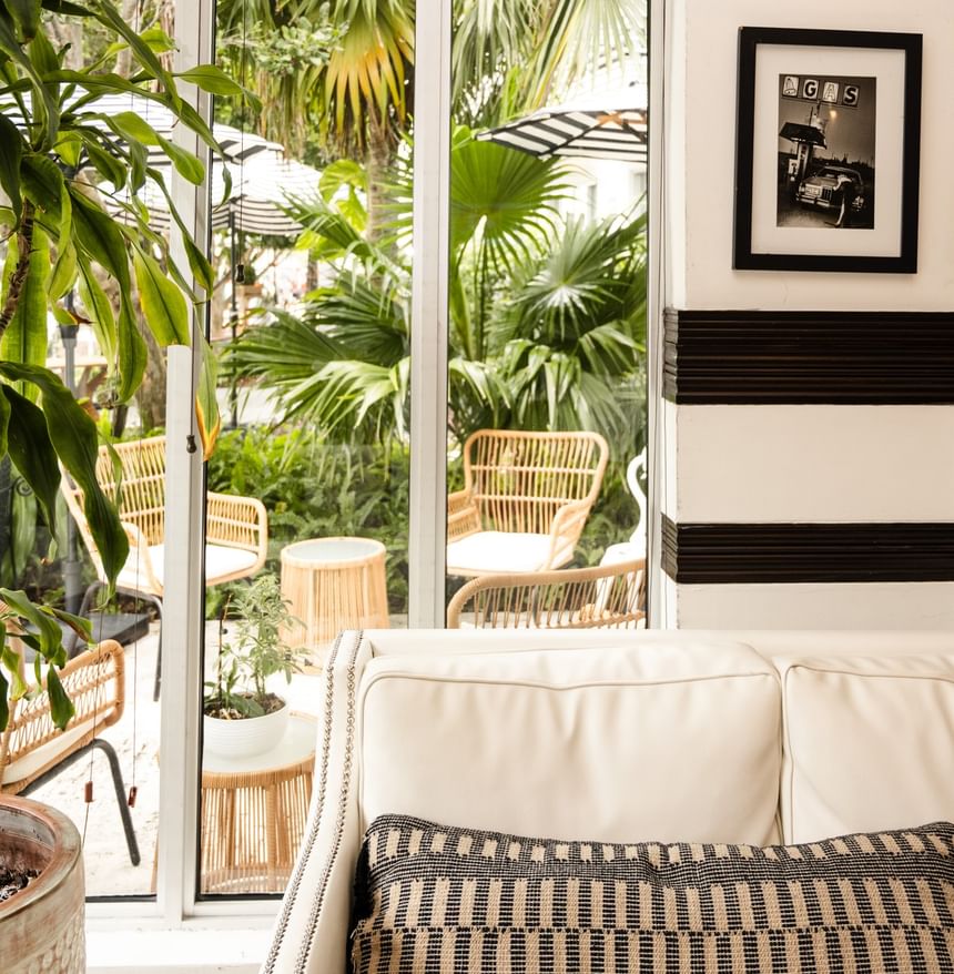 Chic white sofa with patterned pillows overlooking a tropical garden courtyard at the Riviera Hotel South Beach