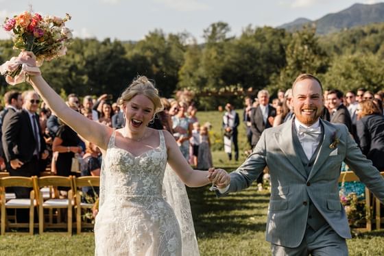 Newlyweds run hand in hand as they finish their wedding ceremony at Topnotch Resort. Photo Credit: Jesse Schloff