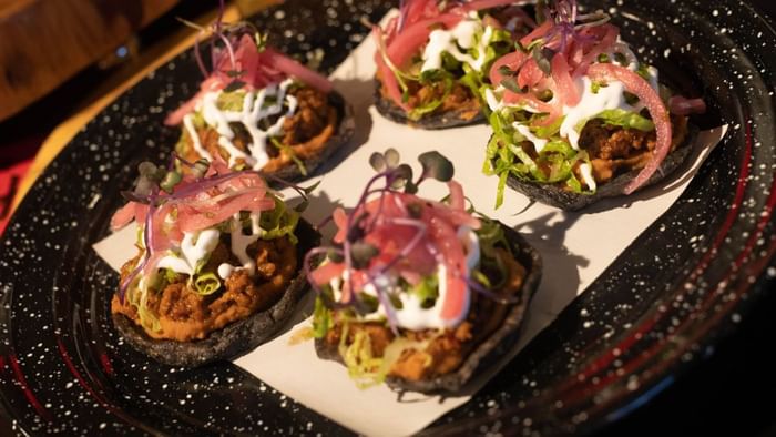 Five mini sopes on blue corn bases topped with cream and pickled red onions in Media Sangre at Araiza Calafia