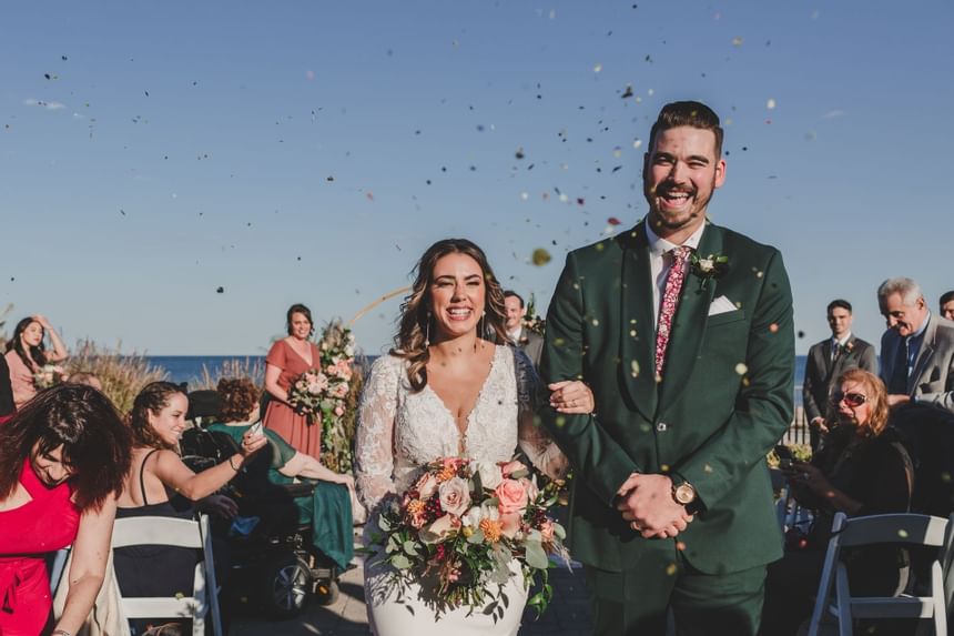 Newlyweds walking in a beach wedding ceremony at Ocean Place