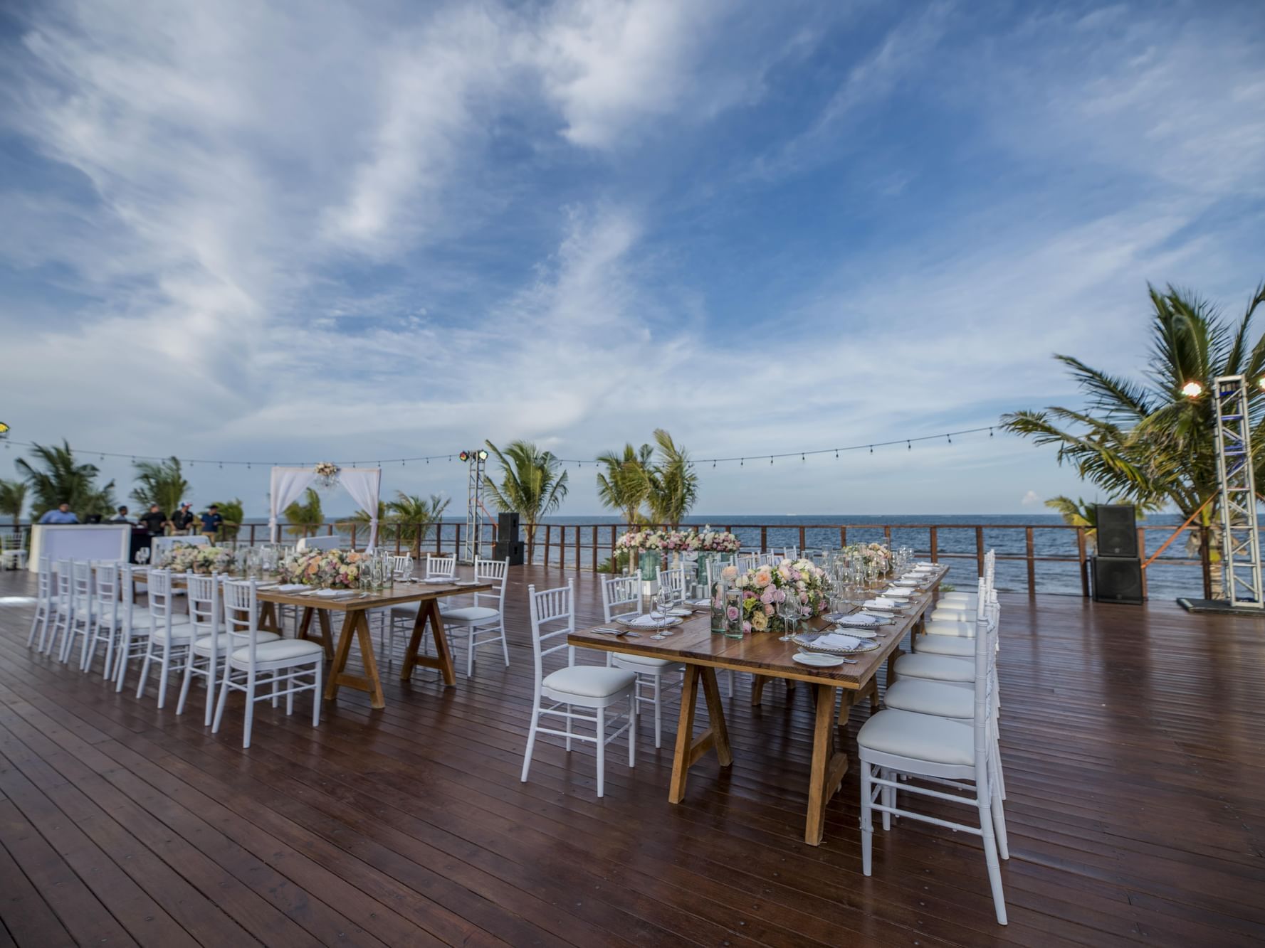 Banquet-style dining set-up with fresh flowers, candles & cutlery on vora deck at Haven Riviera Cancun