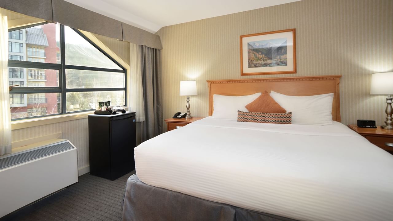 Spacious hotel suite with a king bed, elegant decor and large window for natural light.