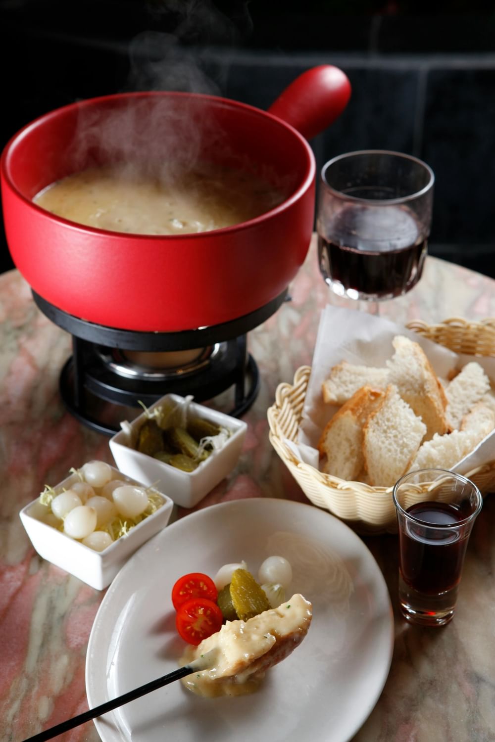 Steaming cheese fondue in a red pot by bread and wine at Warwick Geneva