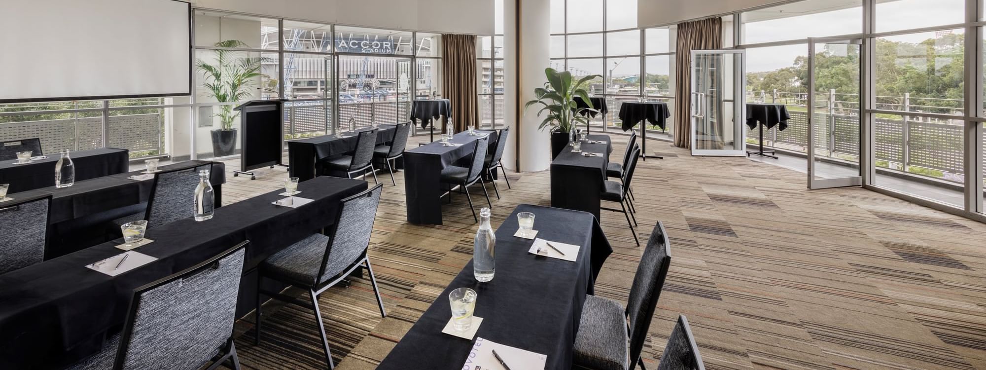 Classroom set-up with projector screen and views of the Accor stadium in Marine Room at Novotel Sydney Olympic Park