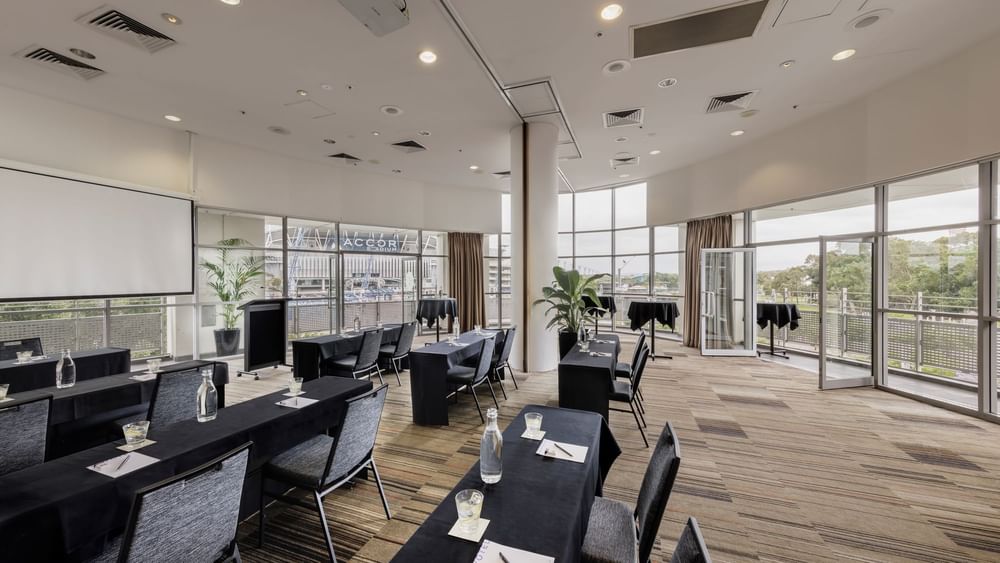 Classroom set-up with projector screen and views of the Accor stadium in Marine Room at Novotel Sydney Olympic Park