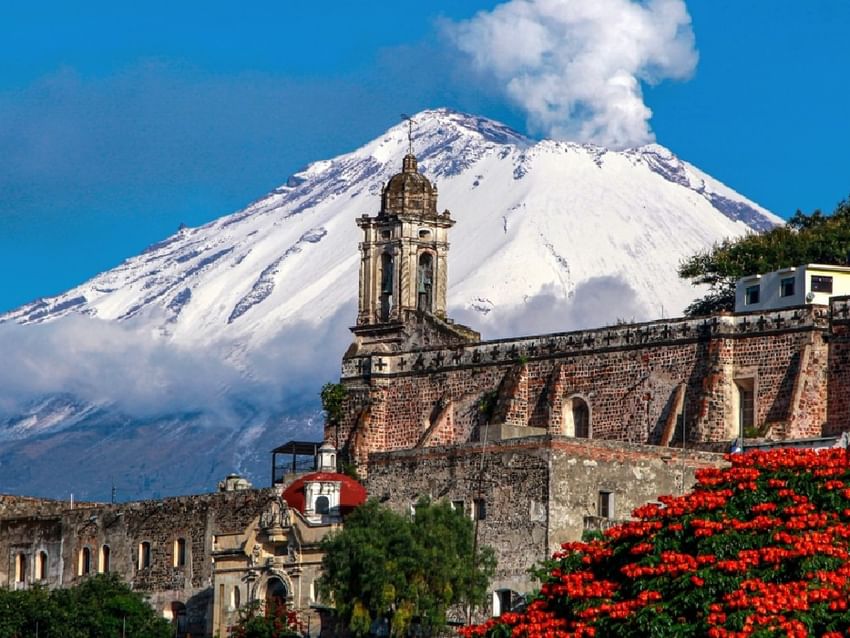 Arquitectura colonial histórica con volcán Popocatépetl nevado al fondo cerca de Camino Real Hotels