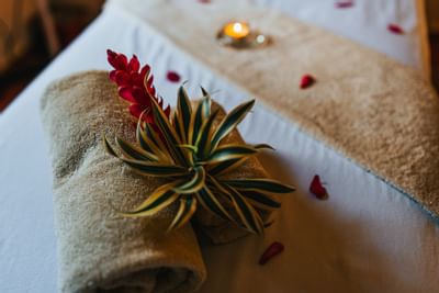 Un rollo de toalla y flores en la cama del spa en el Hotel Los Mandarinos