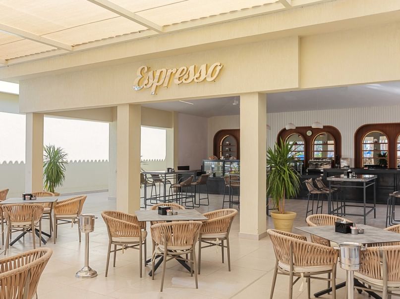 An outdoor restaurant with tables, chairs, and a bar counter with the word 