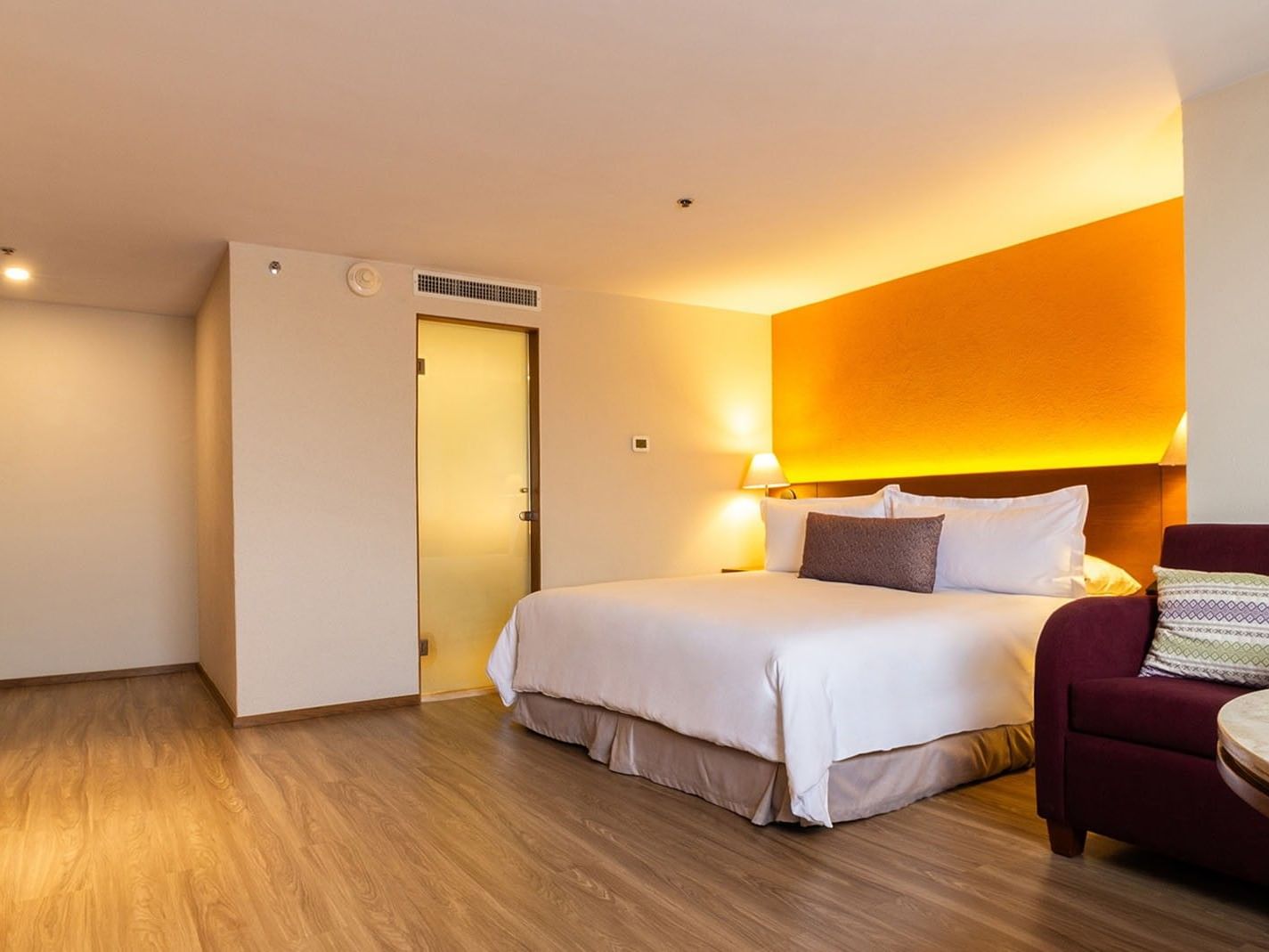 Junior Suite King con cama grande, sofá y mesa en Camino Real Aeropuerto México, Ciudad de México.