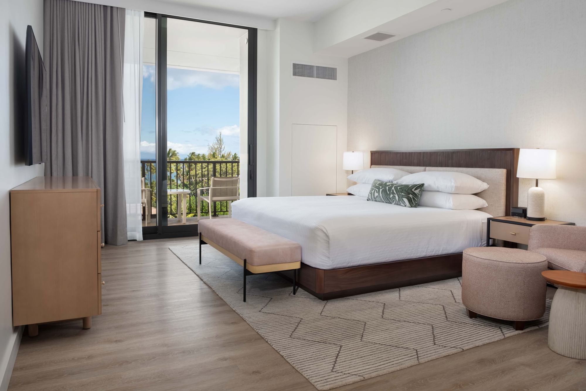 A hotel room with a large bed, balcony, and modern furniture