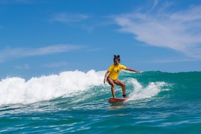 Girl surfing with the beach waves on a sunny day near Paramount Hotels