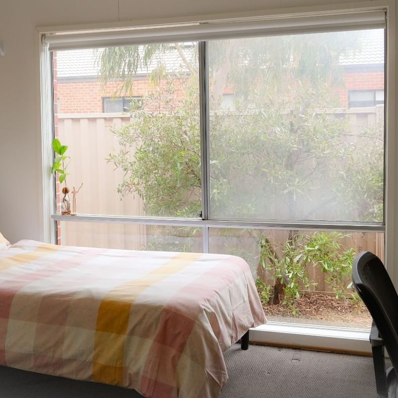 A neat room with a bed, desk, and large window at La Trobe University Regional Housing - Ballarat.