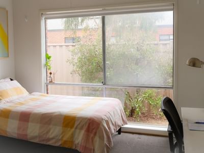 A neat room with a bed, desk, and large window at La Trobe University Regional Housing - Ballarat.