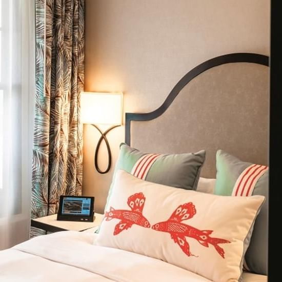 Bedroom with patterned curtains, plush bed, and a decorative pillow at Catalina Island Company, one of the catalina island rooms