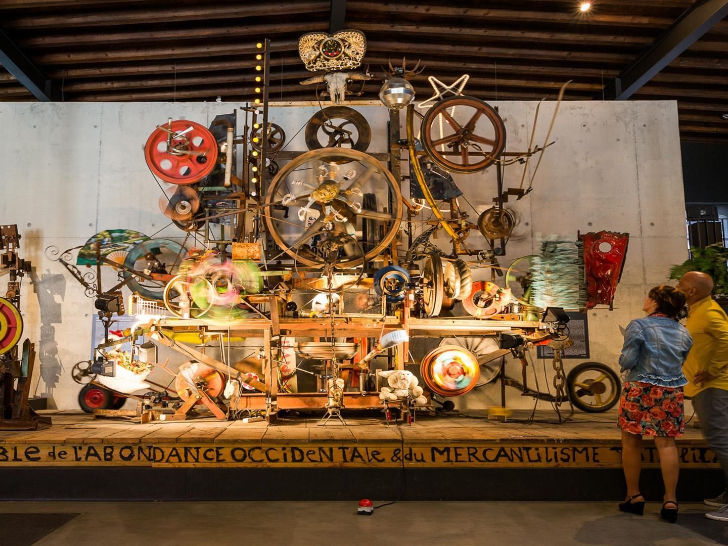 Mechanical art piece with lights and motion set against concrete at Espace Jean Tinguely near Hotel des Innovations