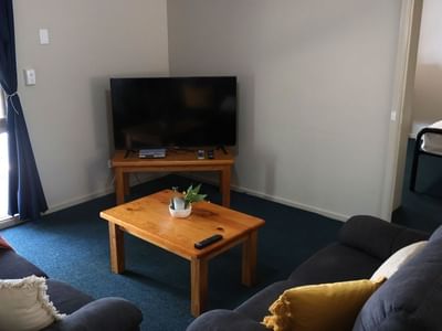 Living room with couch, TV, and wooden table at La Trobe University - Villas.