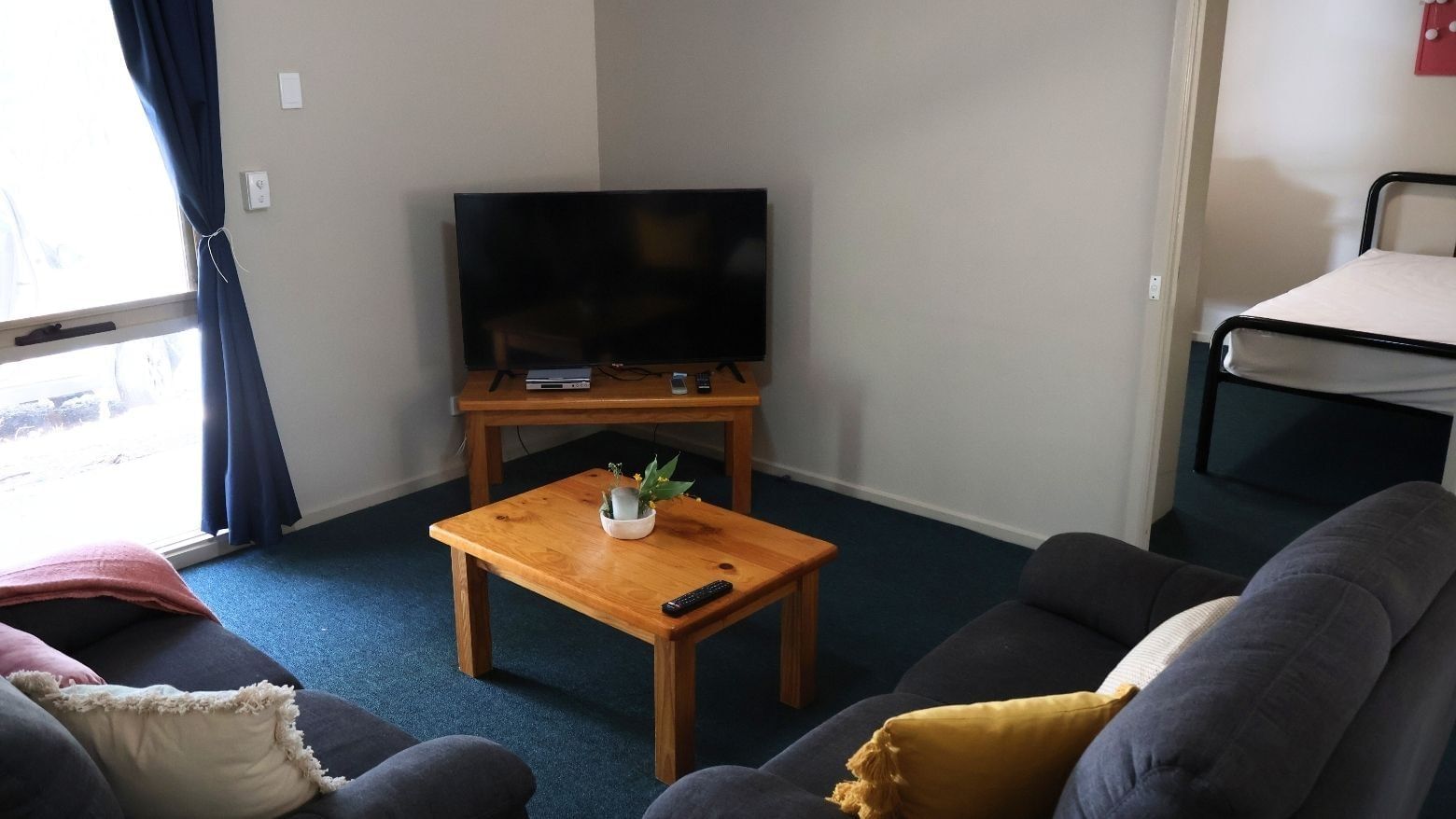 Living room with couch, TV, and wooden table at La Trobe University - Villas.