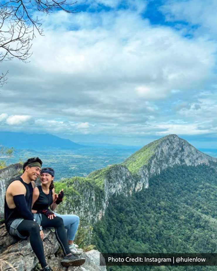 a couple sitting on a rock with a mountain-view behind them - Lexis PD
