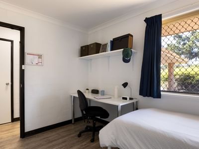 Small room with bed, desk, chair, and window at UniLodge at Curtin University.