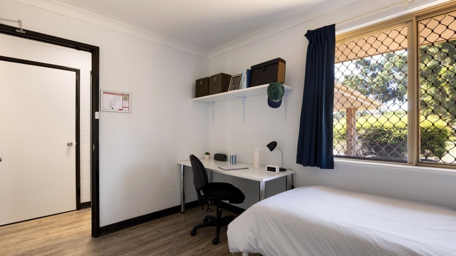 Small room with bed, desk, chair, and window at UniLodge at Curtin University.