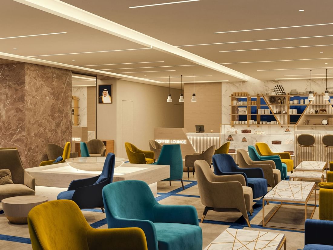 Al Maha Colorful armchairs by marble tables under a warm glow in Al Maha Café at Cantonal Hotel by Warwick Riyadh