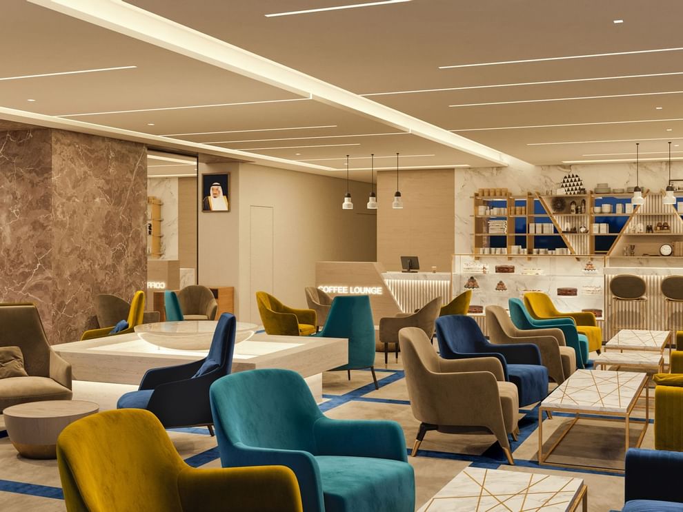 Al Maha Colorful armchairs by marble tables under a warm glow in Al Maha Café at Cantonal Hotel by Warwick Riyadh