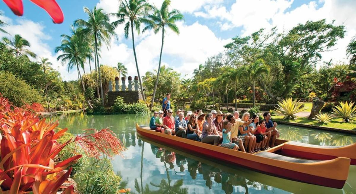 A group of people in a canoe on a pond surrounded by tropical plants and trees.