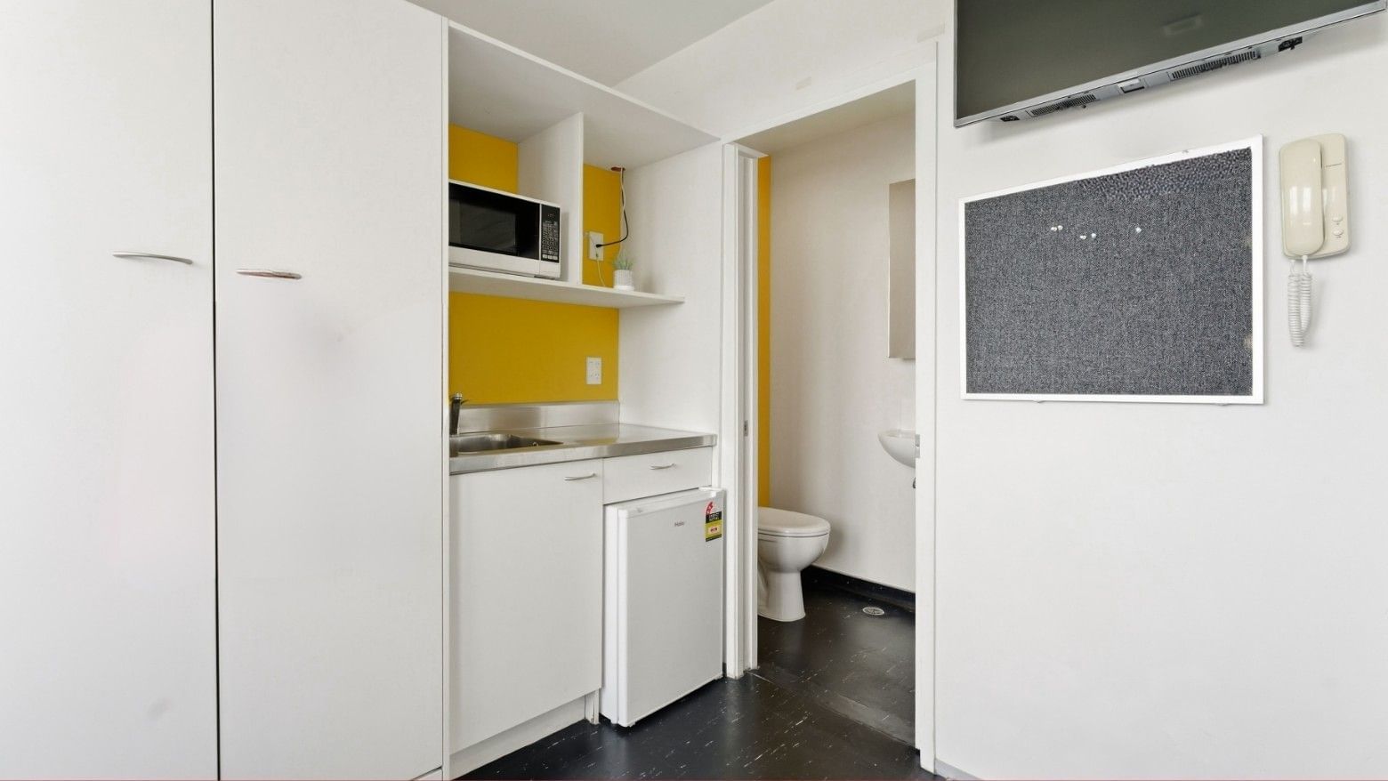 Modern compact kitchen with microwave, fridge, sink, and TV at Student Living Auckland Anzac.