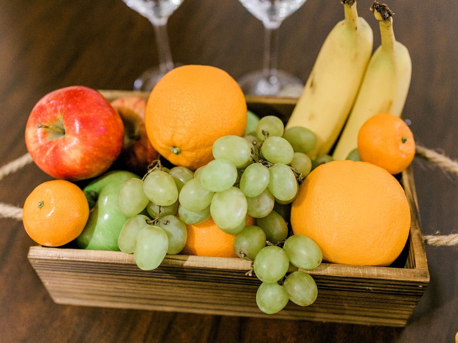 basket of fruit and wine glasses on table