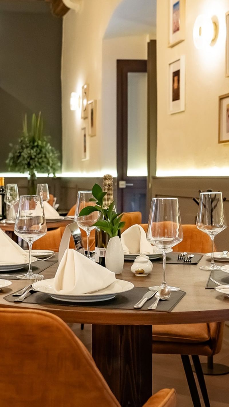 Sophisticated restaurant table setting with white linens, wine glasses, & leather chairs in Tierra Mía at Quinta Real Puebla