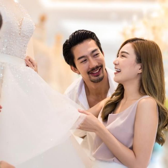 Couple at wedding fair looking at a dress featuring our article on 