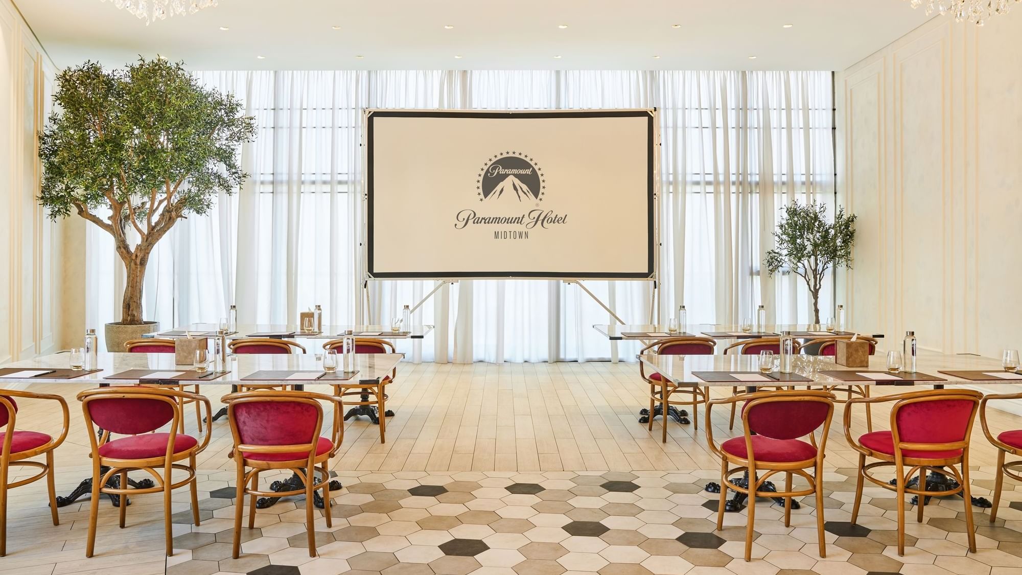 Paparazzi restaurant venue at Paramount Hotel Midtown, arranged with tables and chairs facing a projector screen