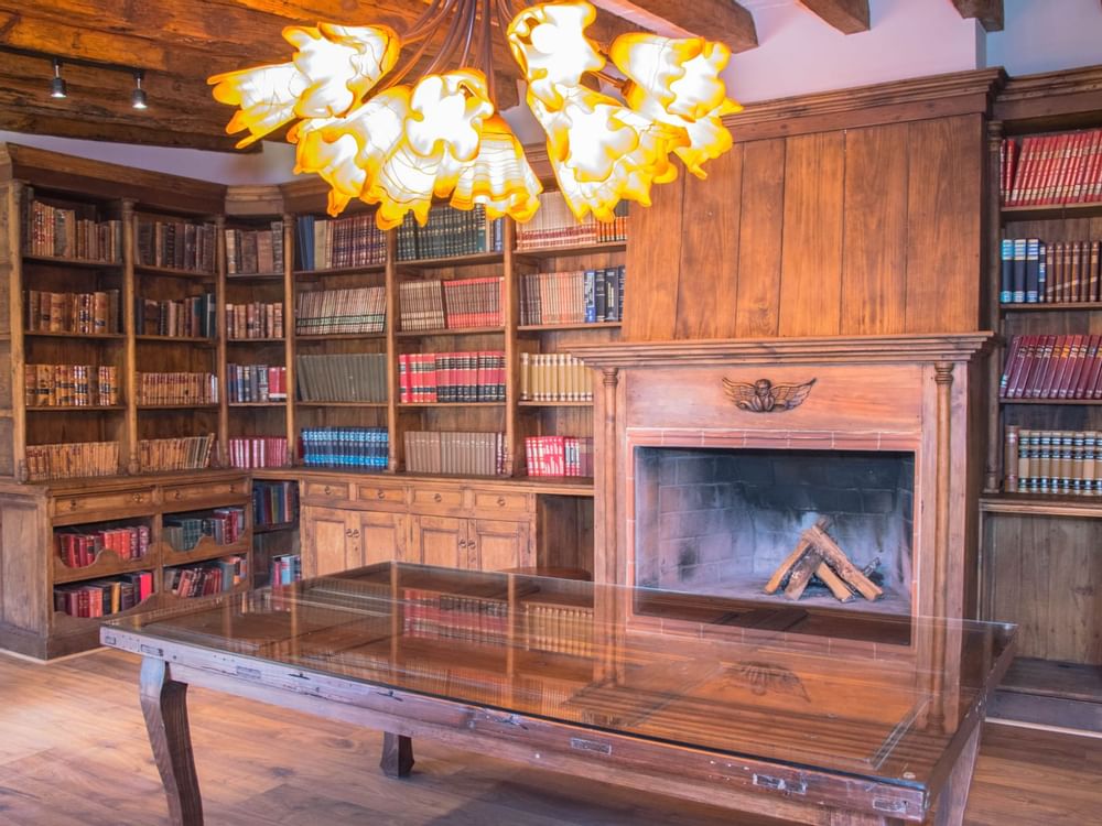 Bookshelf & a fireplace in Biblioteca Stanza at Gamma Hotels