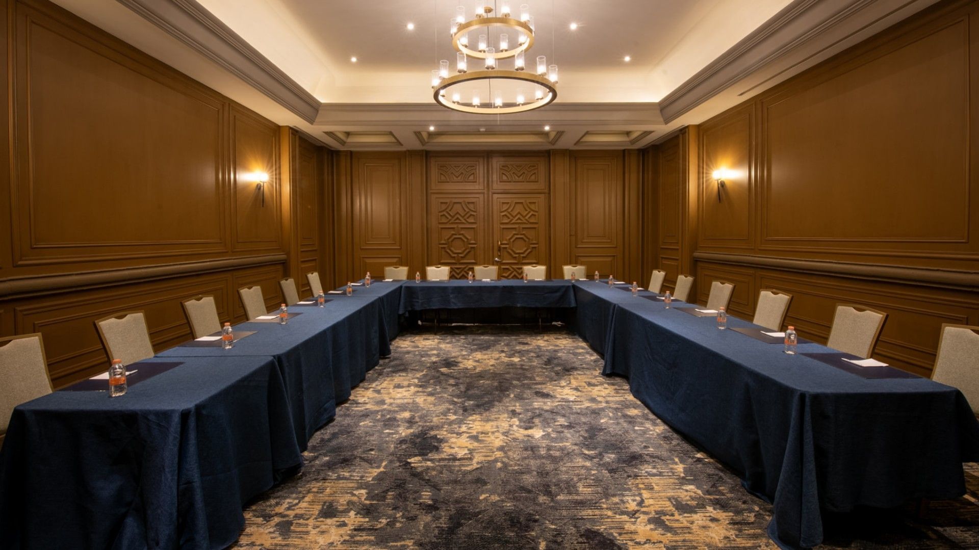 Salon Marques with a large U-shaped table, blue cloths, and wood paneling at Quinta Real Monterrey