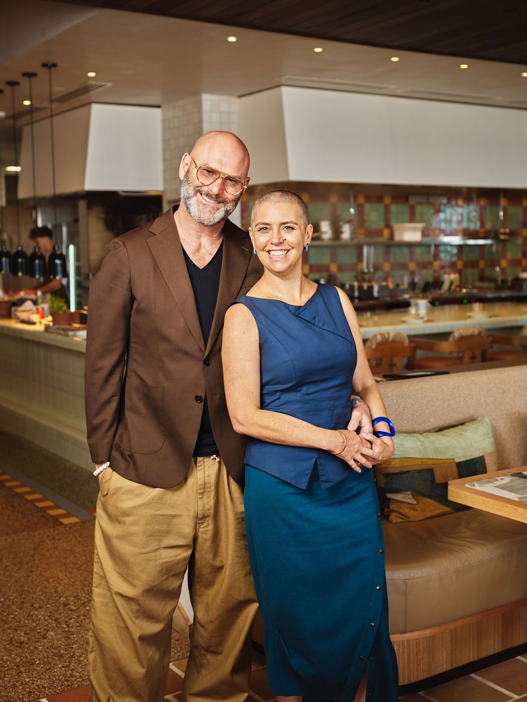 Cibaria Manly at Elysium Manly, featuring a smiling couple standing by a bench seat under an open kitchen view