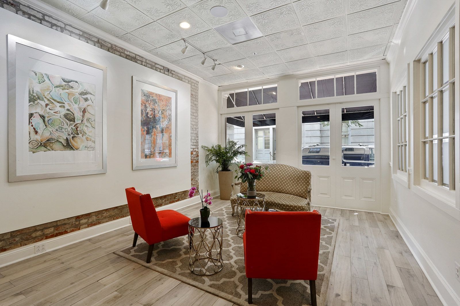 A bright and inviting lobby with red chairs, artwork, and a coffee table.