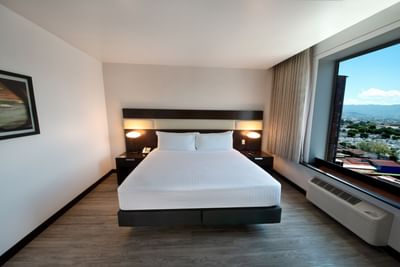 1 King Bed, Premium Room with two nightstands between bed and window with city view at San Jose Costa Rica Hotel