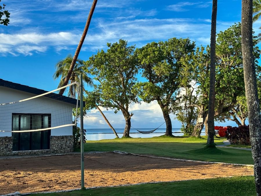 Beachfront volleyball court with tropical trees and hammock at The Naviti Resort - Fiji.
