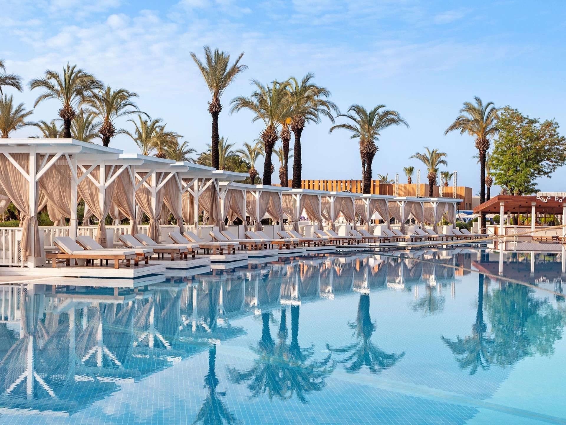 An outdoor pool with pier huts and sun beds arranged at Titanic Deluxe Lara