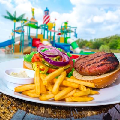 A juicy grilled burger and golden French fries served on a plate in the Oasis Grill at Centennial Plaza Resort