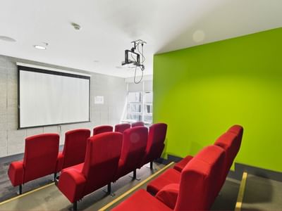 Empty room with red chairs and a projector screen at Student Living Auckland – Anzac.