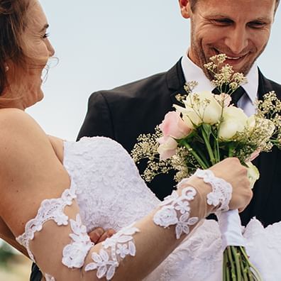 Groom carrying bride with bouquet at Coast Hinton Hotel