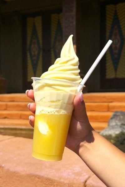 A hand holds a plant-based Dole Whip treat in a cup, one of the best plant-based foods in Orlando.